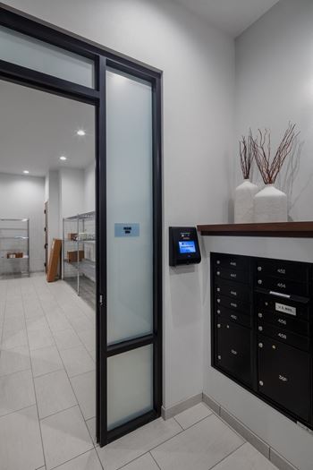 A glass door leading into a room with a mail room and a counter with mail